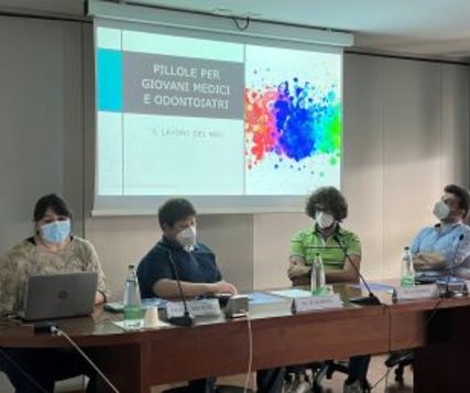 quattro medici seduti al tavolo dei relatori durante un convegno